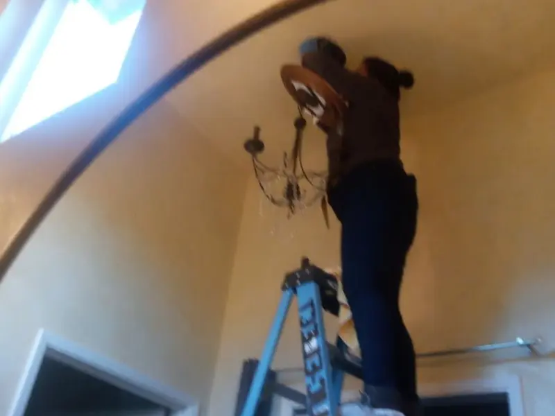 Electrician installing a chandelier in a Veneta residence